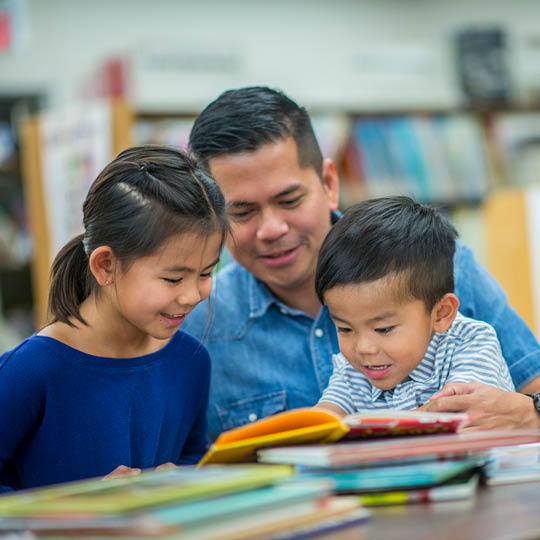 Asian father with son and daughter in a library 